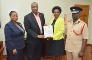 Minister of State, Mr. Joseph Harmon receives the report from Commissioner, Retired Colonel Windee Algernon, Minister of Social Protection, Ms. Volda Lawrence and Acting Chief Fire Officer, Mr. Winston McGregor (right) also received copies of the report.