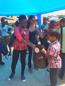 Child receiving backpack and stationery supplies
