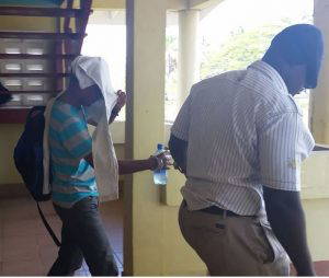 Officers Bharrat Chatterpaul & Delroy Fraser covering their faces as they exit the court room on Thursday